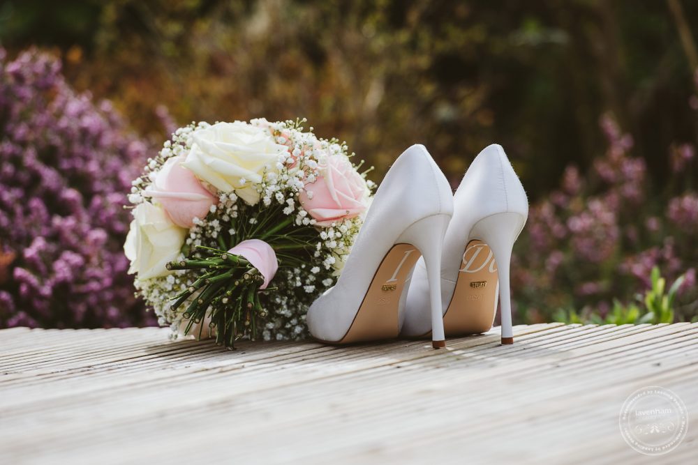 The bride's wedding shoes photographed in detail in front of pink flowerbeds