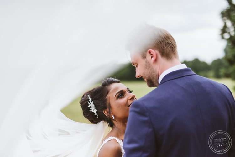 Dramatic wedding photo with the bride's veil flying through the frame