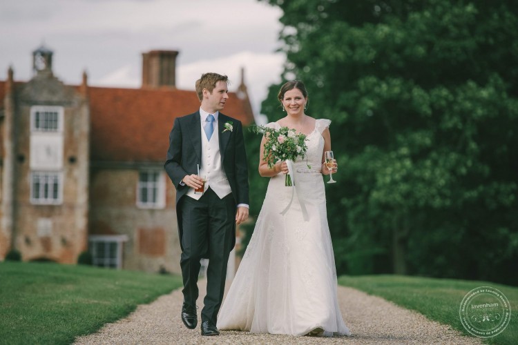 Bride and groom walking in front of Bruisyard Hall, Suffolk. Photography by Lavenham Photographed