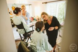 Bride getting her makeup done in a bright, airy room before her wedding, with a professional makeup artist and bridesmaids helping her prepare at an Essex and Suffolk wedding. Beautiful wedding makeup and preparations in a bright room at a wedding venue in Essex & Suffolk, capturing intimate moments of the bride getting ready for her special day.