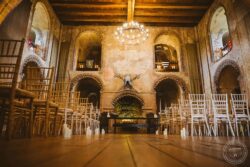 Charming historic stone hall with medieval decor and elegant seating arrangement for a wedding ceremony in Essex or Suffolk. Elegant medieval wedding ceremony setup inside a historic stone hall, with wooden chairs, candles, and atmospheric lighting, perfect for a romantic Essex or Suffolk wedding.