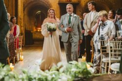 A heartfelt moment during a wedding ceremony at a historic Essex venue, featuring emotional family members, beautiful decor, and guests in formal attire celebrating love and commitment. Elegant bride walking down the aisle with her father in a historic Essex wedding venue, surrounded by family and friends celebrating their special day.